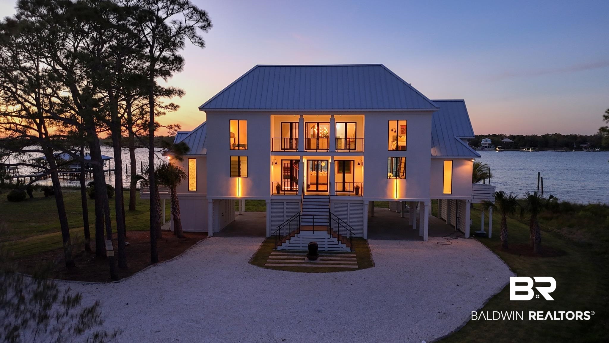 33349 River Road Orange Beach, AL 36561 - Photo 46 of 61 Stilt-raised modern coastal residence featuring multiple balconies, a metal roof, and a gravel driveway