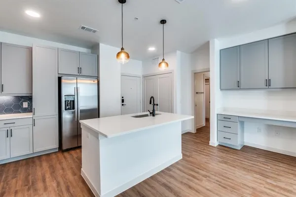 a kitchen with a refrigerator a sink and wooden floor
