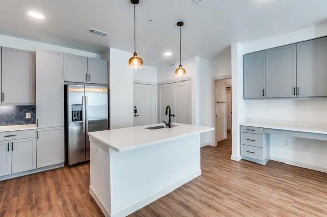 a kitchen with a refrigerator a sink and wooden floor