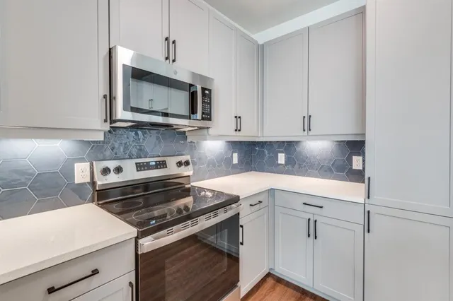 a large kitchen with kitchen island a stove a sink a center island and wooden floor