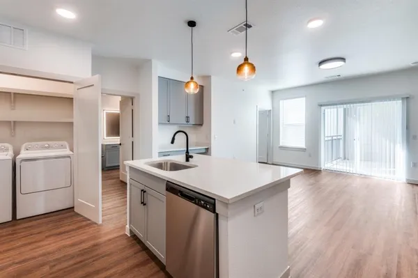 a kitchen with a sink stove and wooden floor