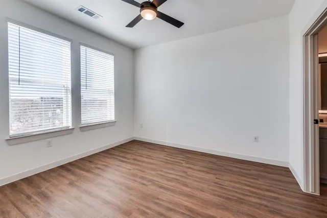 an empty room with wooden floor and windows