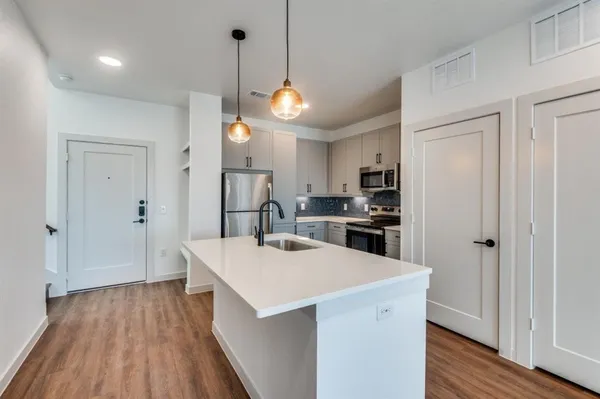 a view of kitchen with kitchen island wooden floors and stainless steel appliances