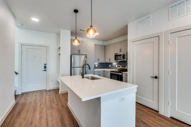 a view of kitchen with kitchen island wooden floors and stainless steel appliances