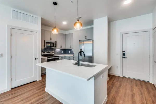 a kitchen that has a sink stainless steel appliances and wooden floor