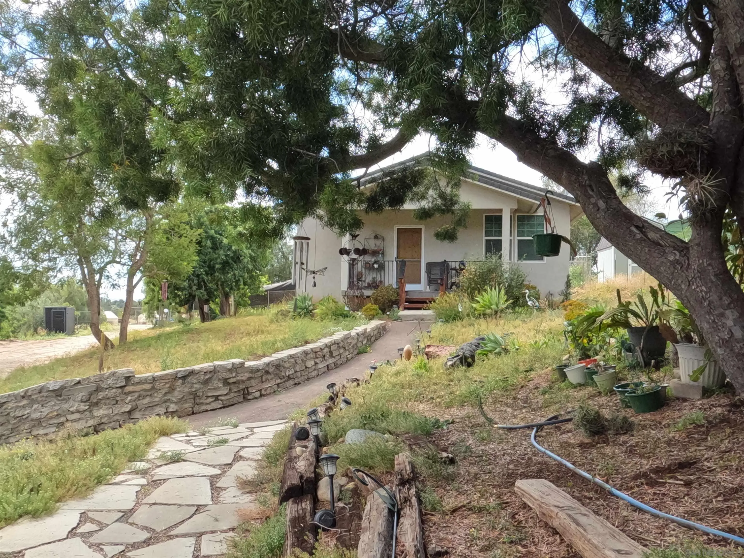 202 North Stage Coach Lane Fallbrook, CA 92028 - Photo 3 of 26 a front view of a house with a yard and large trees