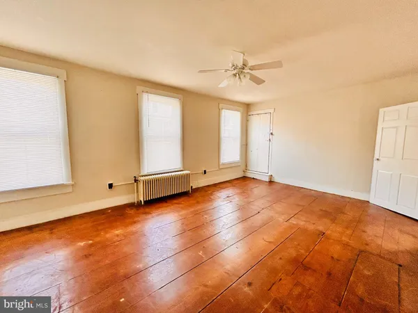 an empty room with chandelier fan and windows