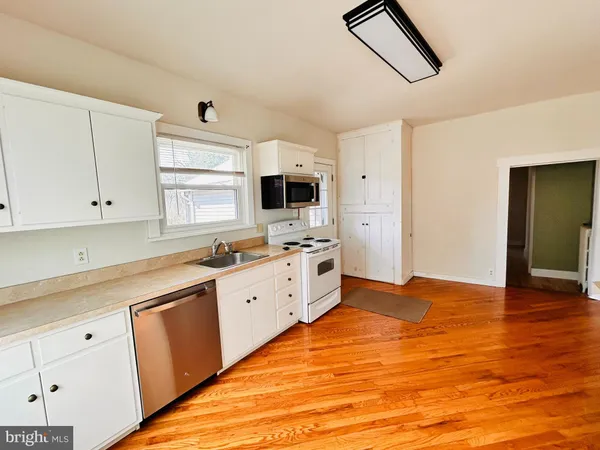 a large white kitchen with stainless steel appliances granite countertop a stove and a sink