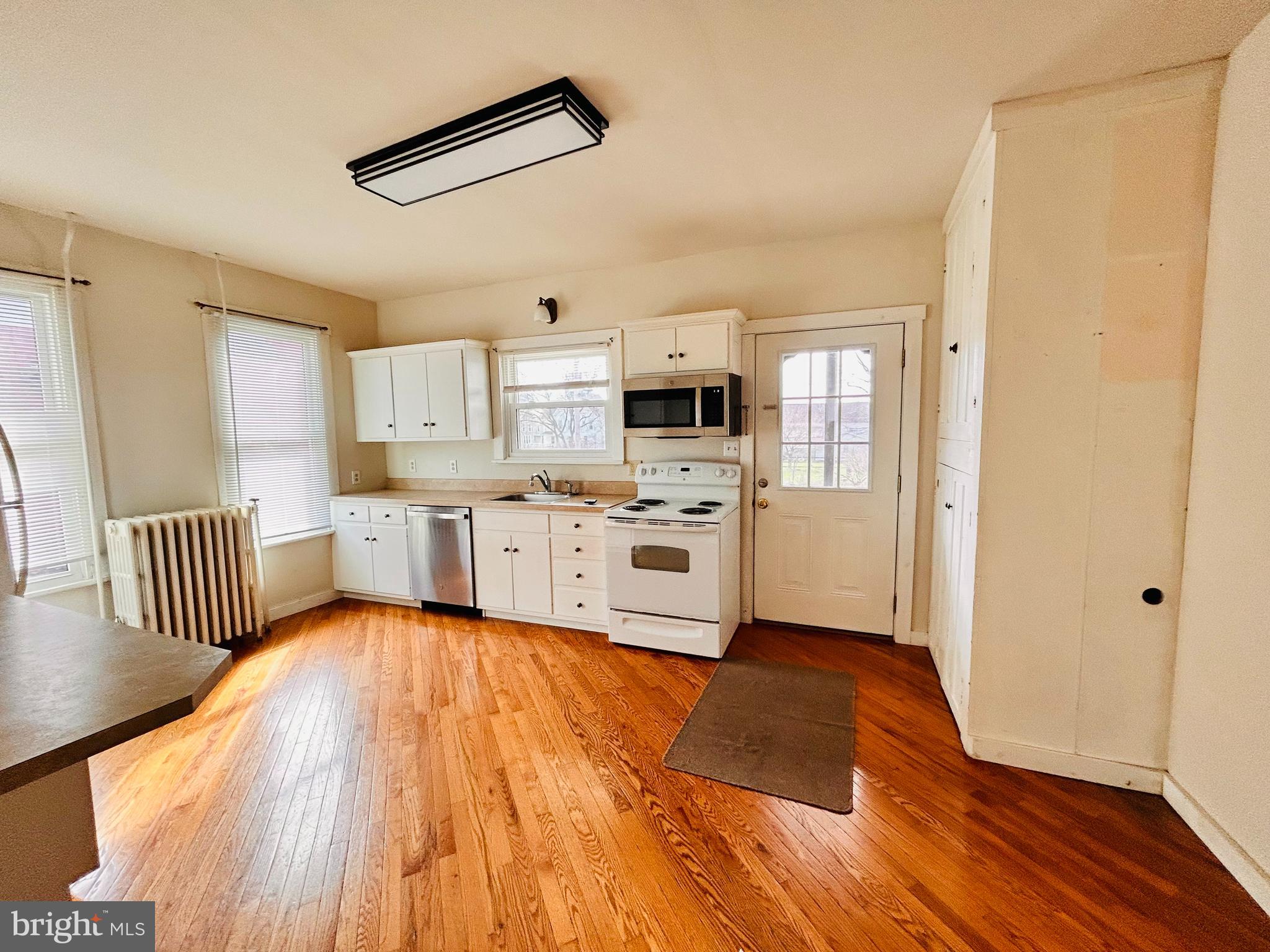 113 West Main Street Millheim, PA 16854 - Photo 9 of 30 a large white kitchen with wooden floors and stainless steel appliances