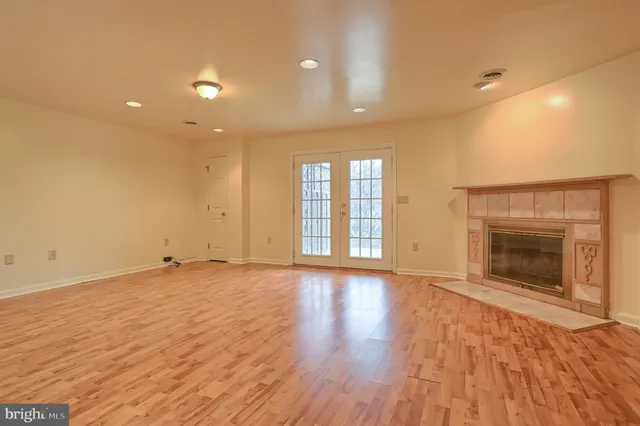 a view of an empty room with wooden floor and a fireplace
