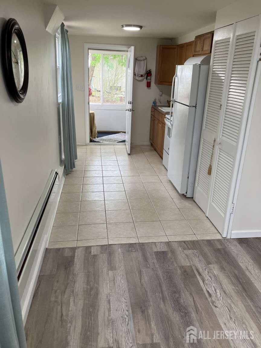 141 Dunbar Avenue Fords, NJ 08863 - Photo 12 of 25 a view of a refrigerator in kitchen and an empty room with wooden floor