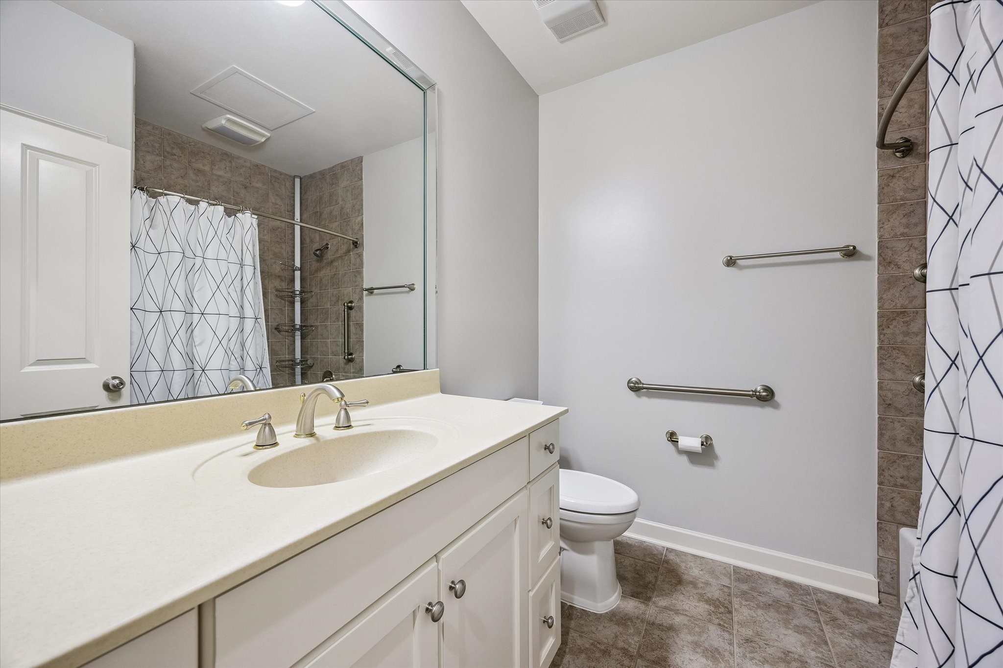914 Main Street, Unit 910 Houston, TX 77002 - Photo 16 of 32 This bathroom features a modern design with a large mirror, a sleek countertop with a single sink, and ample cabinet storage. It includes a tub shower combo.
