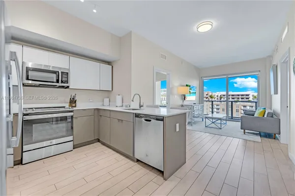 a large kitchen with stainless steel appliances kitchen island granite countertop a refrigerator and a sink