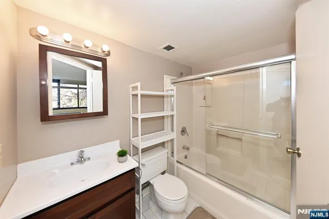 a bathroom with a sink a toilet a mirror and shower