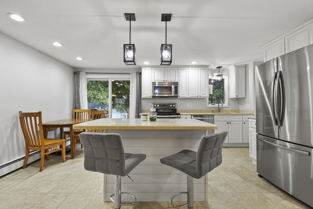 26 Westwood Road Webster, MA 01570 - Photo 6 of 30 a kitchen with stainless steel appliances granite countertop a stove a refrigerator a oven a sink a dining table and chairs with wooden floor