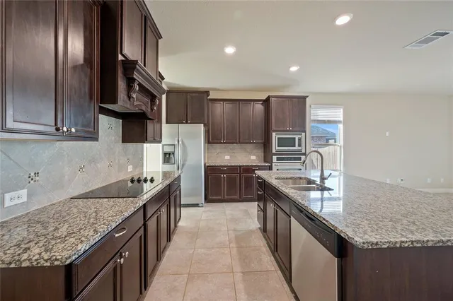 a large kitchen with stainless steel appliances granite countertop a sink stove and refrigerator