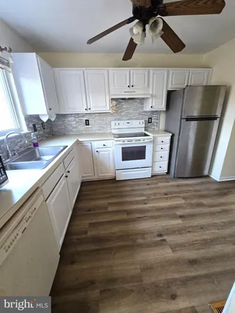 a kitchen with stainless steel appliances a refrigerator a sink and white cabinets