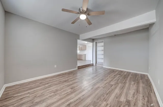 a view of an empty room with window and wooden floor