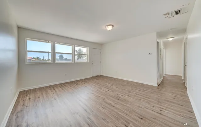 an empty room with wooden floor and windows