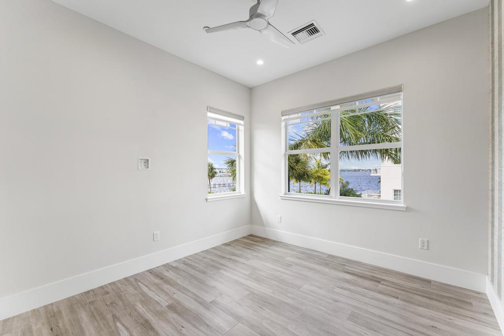 53 Southeast Seminole Street, Unit A Stuart, FL 34994 - Photo 45 of 75 an empty room with wooden floor chandelier fan and windows