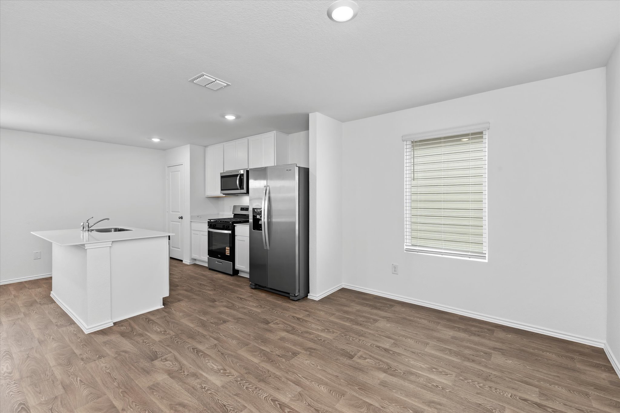 456 Sandringham Loop Kyle, TX 78640 - Photo 6 of 40 A contemporary kitchen and living area featuring stainless steel appliances and durable wood-look flooring.