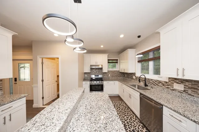 a large kitchen with stainless steel appliances granite countertop a sink stove and cabinets