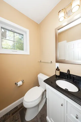 a bathroom with a granite countertop toilet a sink and a mirror