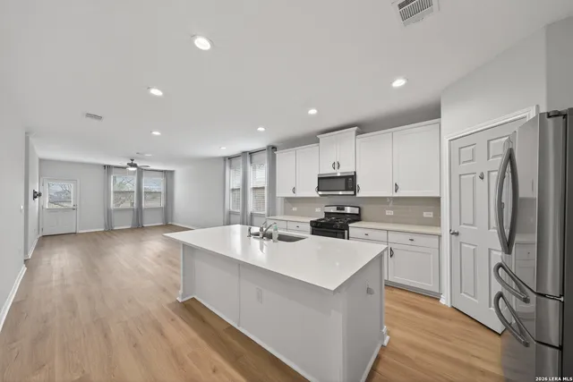 a kitchen with a sink a refrigerator and wooden floor