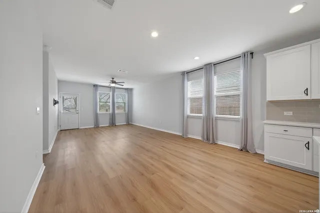 a view of an empty room with window and wooden floor
