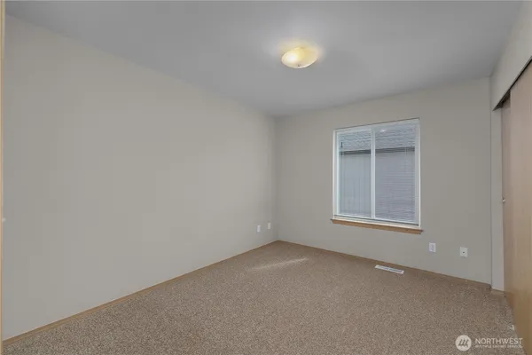 a view of an empty room with closet and a window