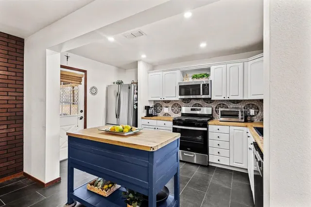 a kitchen with stainless steel appliances granite countertop a stove refrigerator sink and microwave