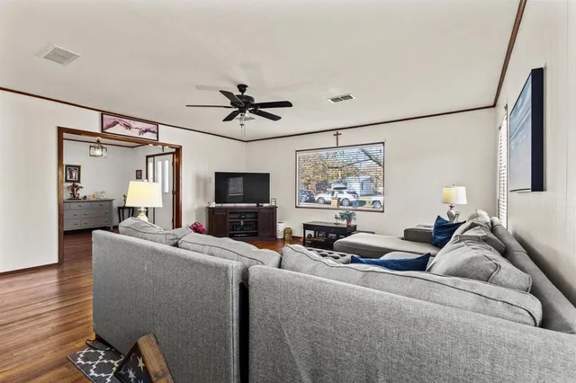 a living room with furniture a ceiling fan and a flat screen tv