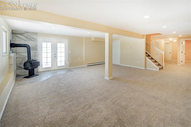 17879 Pinon Park Road Peyton, CO 80831 - Photo 19 of 26 Spacious walk out basement includes new paint, carpet, wood burning stove, large room perfect for a office/craft room or workout room, full bathroom, laundry, storage room and access to garage.