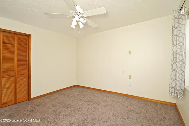 an empty room with a ceiling fan and a window
