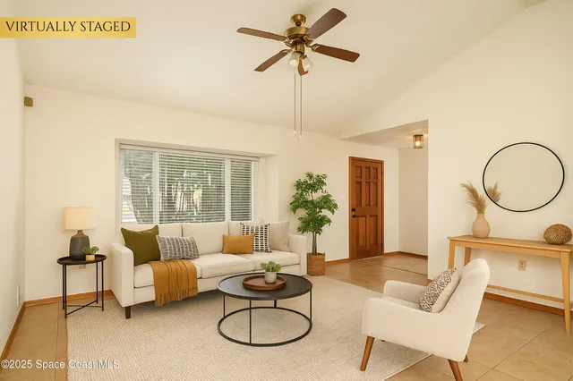 a living room with furniture a chandelier fan and a window
