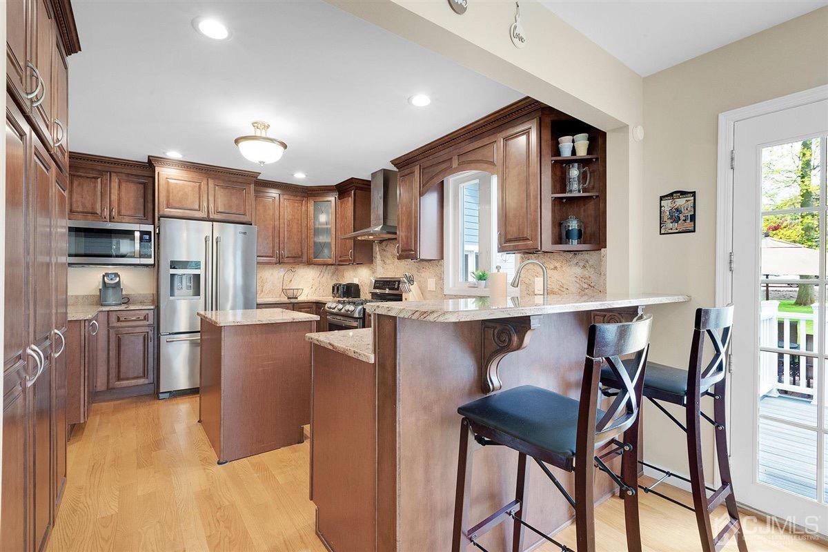23 Southfield Road Edison, NJ 08820 - Photo 15 of 57 a open kitchen with stainless steel appliances granite countertop a refrigerator a stove a sink a dining table and chairs with wooden floor