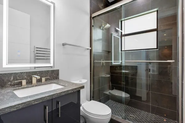 a bathroom with a granite countertop sink toilet a mirror and shower