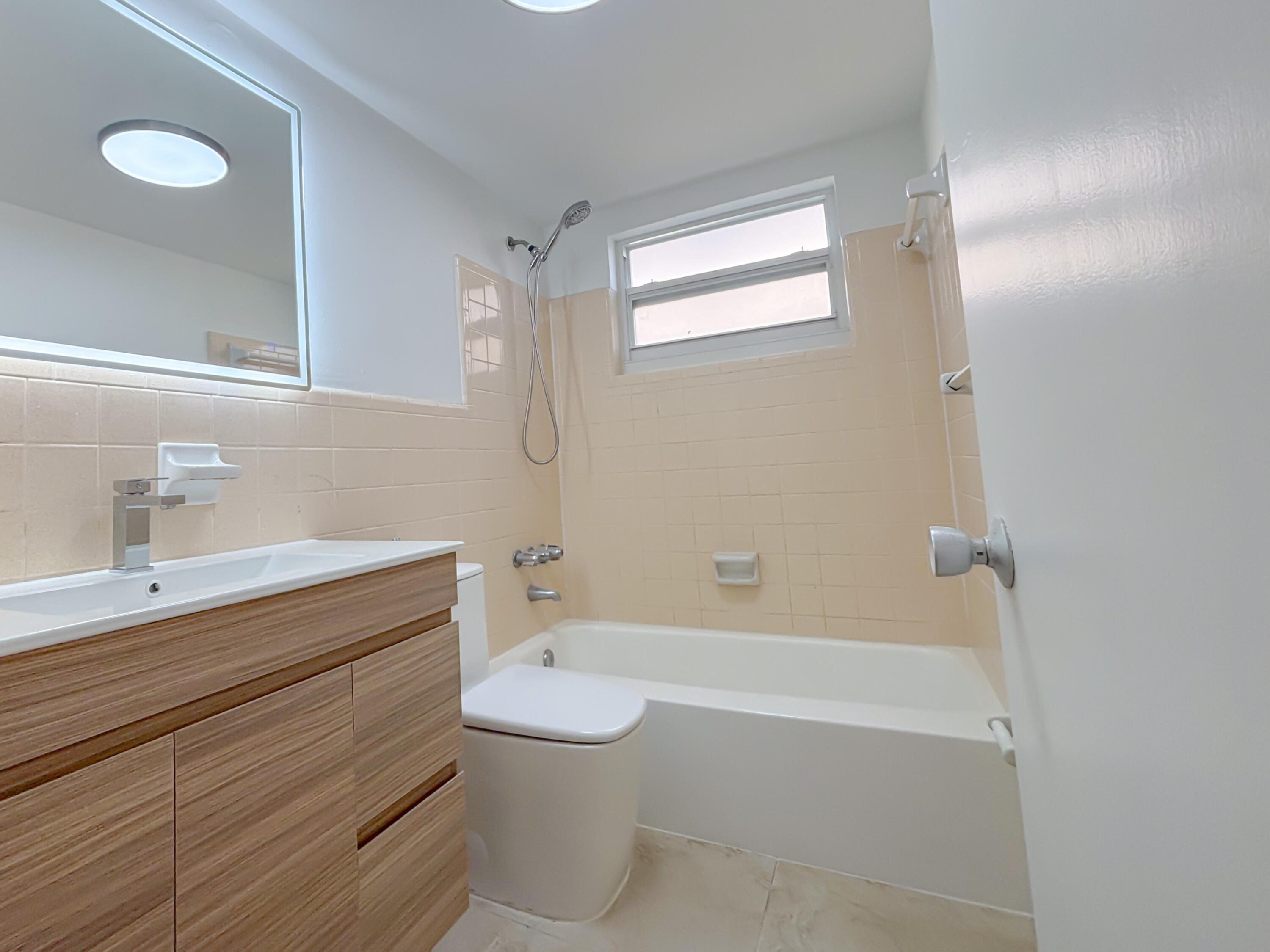 2131 Northeast 40th Court, Unit 1 Lighthouse Point, FL 33064 - Photo 11 of 16 a bathroom with a toilet a sink and bathtub