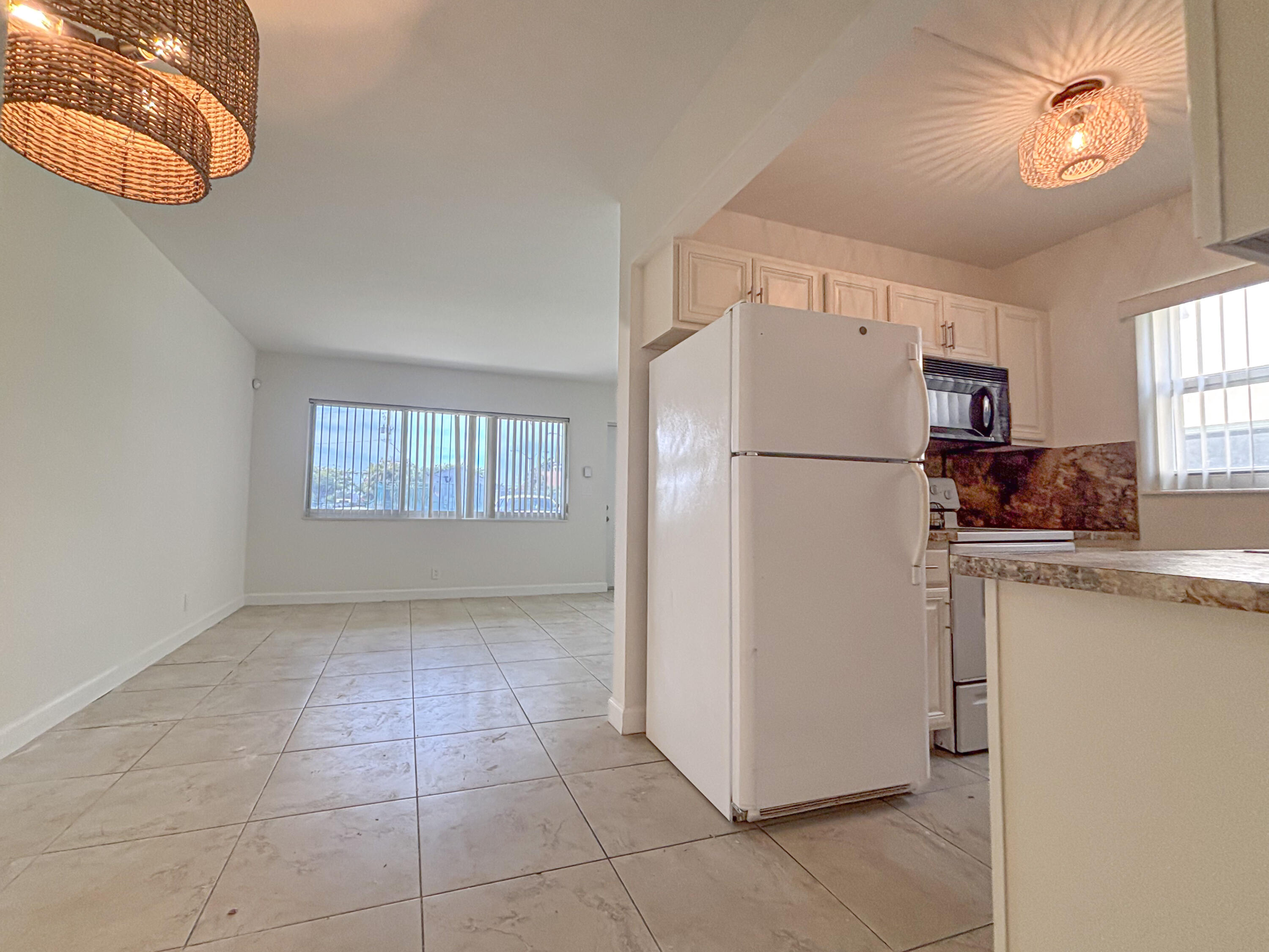 2131 Northeast 40th Court, Unit 1 Lighthouse Point, FL 33064 - Photo 8 of 16 a white refrigerator freezer sitting in a kitchen with cabinets and a refrigerator