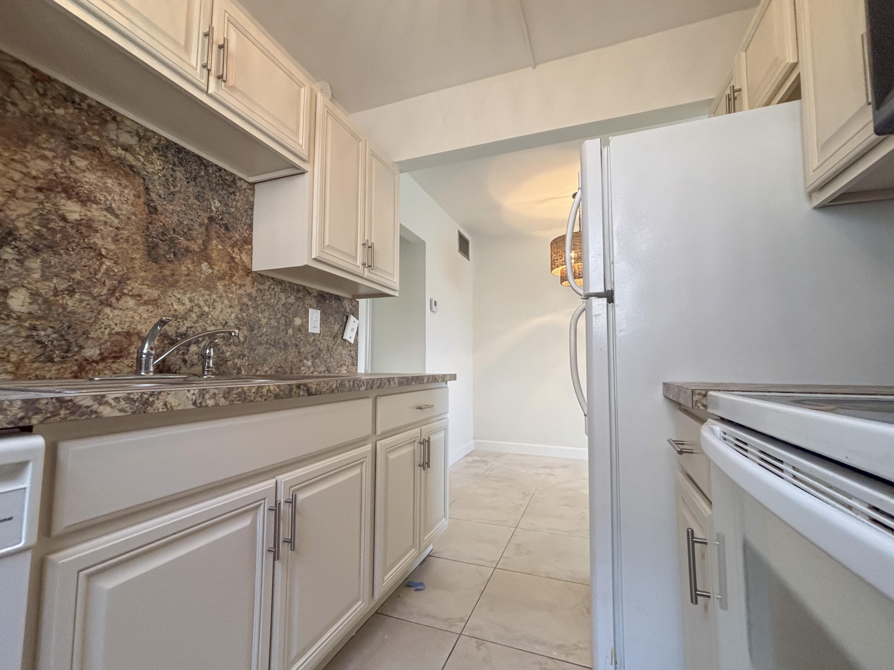 2131 Northeast 40th Court, Unit 1 Lighthouse Point, FL 33064 - Photo 9 of 16 a kitchen with granite countertop white cabinets and white appliances