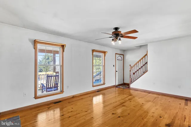 a view of an empty room with wooden floor and a chandelier