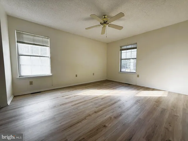 an empty room with wooden floor and windows