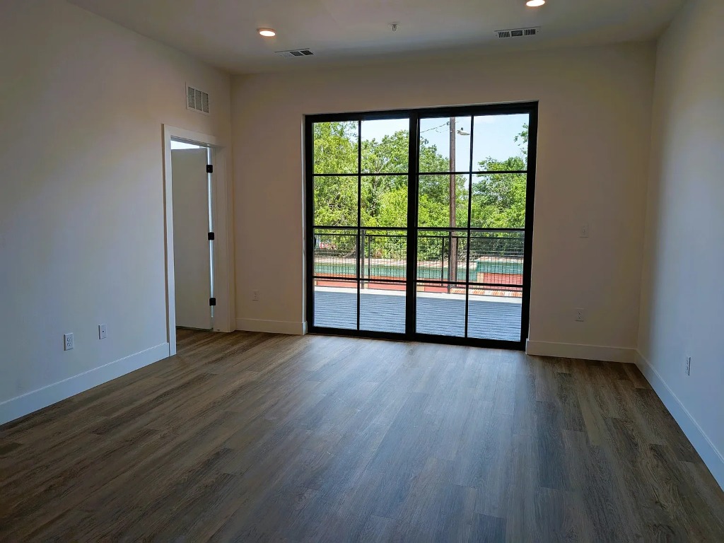 4315 South Congress Avenue, Unit 233 Austin, TX 78745 - Photo 5 of 25 an empty room with wooden floor and windows