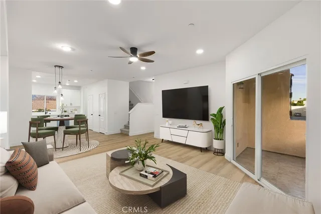 a living room with furniture kitchen view and a wooden floor