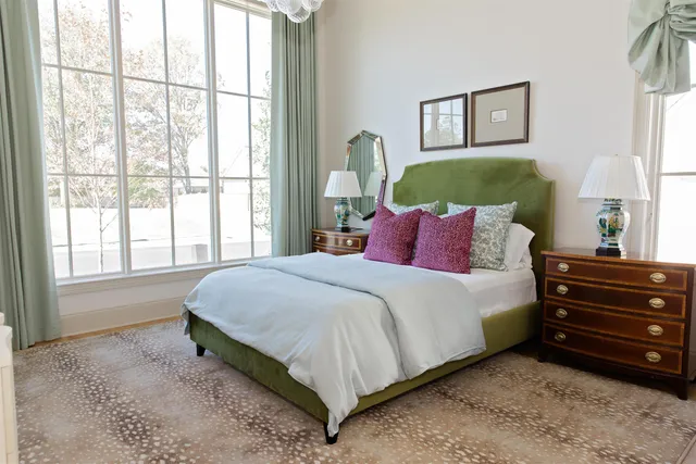 a bedroom with a bed next to a window and a lamp on dresser