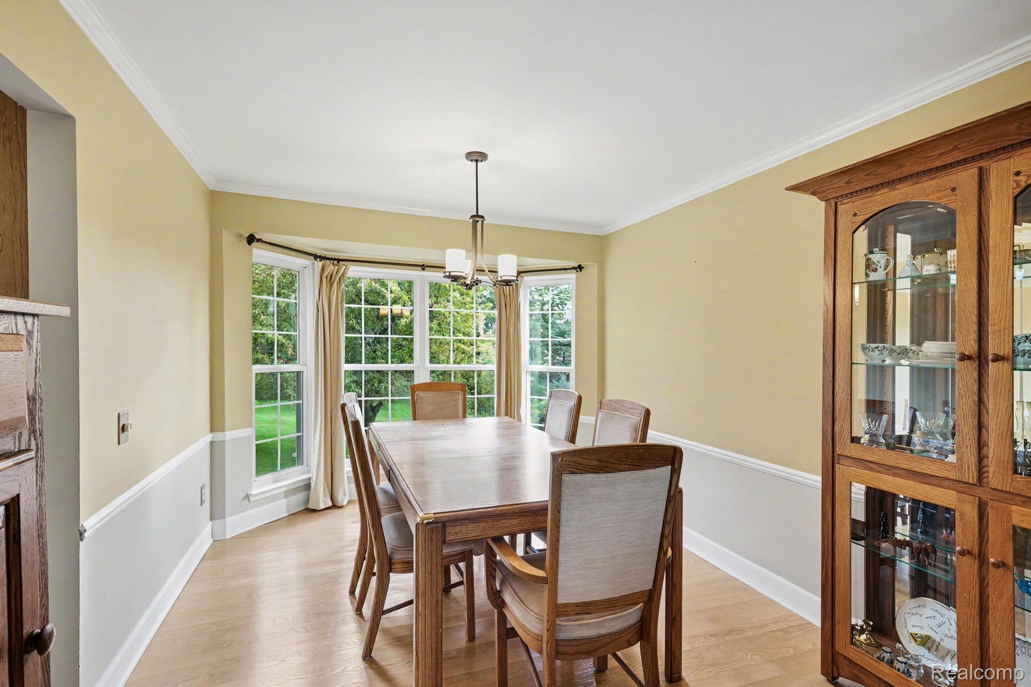 1692 Ridgecrest Rochester, MI 48306 - Photo 6 of 31 Bay window with multiple panes, wood-finish flooring, two-tone wall treatment, crown molding, and a modern chandelier