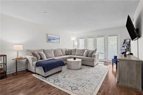 a living room with furniture a flat screen tv and a wooden floor