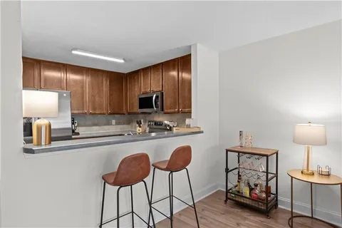 a kitchen with stainless steel appliances granite countertop a stove a sink cabinets and a dining table