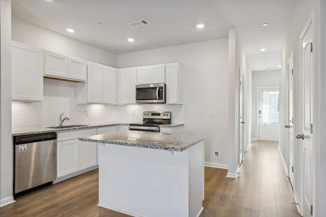 a kitchen with stainless steel appliances granite countertop a sink a stove a refrigerator and cabinets