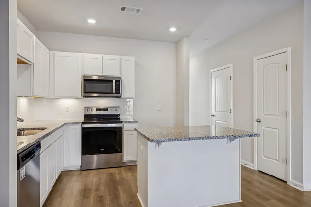 a kitchen with stainless steel appliances granite countertop a stove a sink and a refrigerator